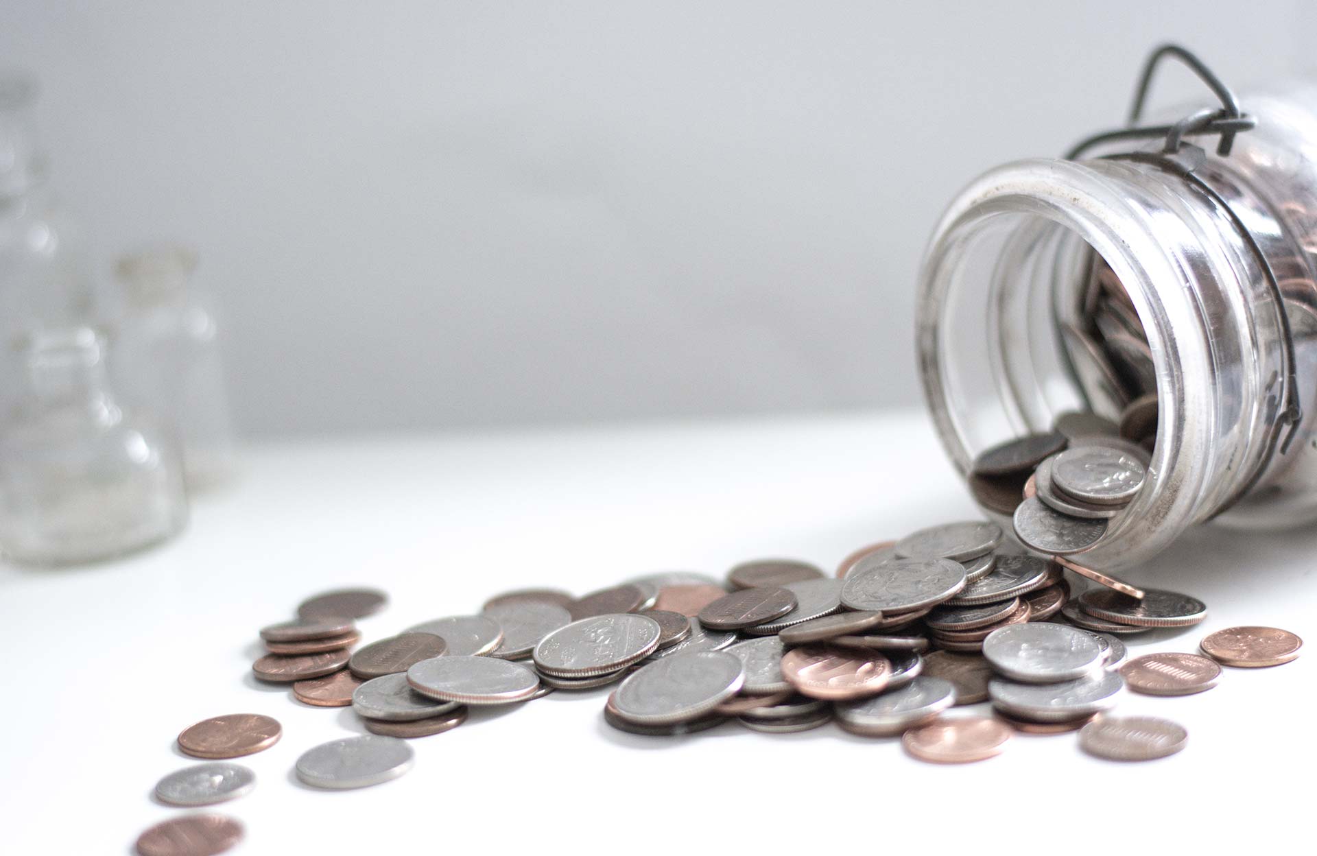 Money jar spilling coins on to a table showing how much money chiller maintenance saves