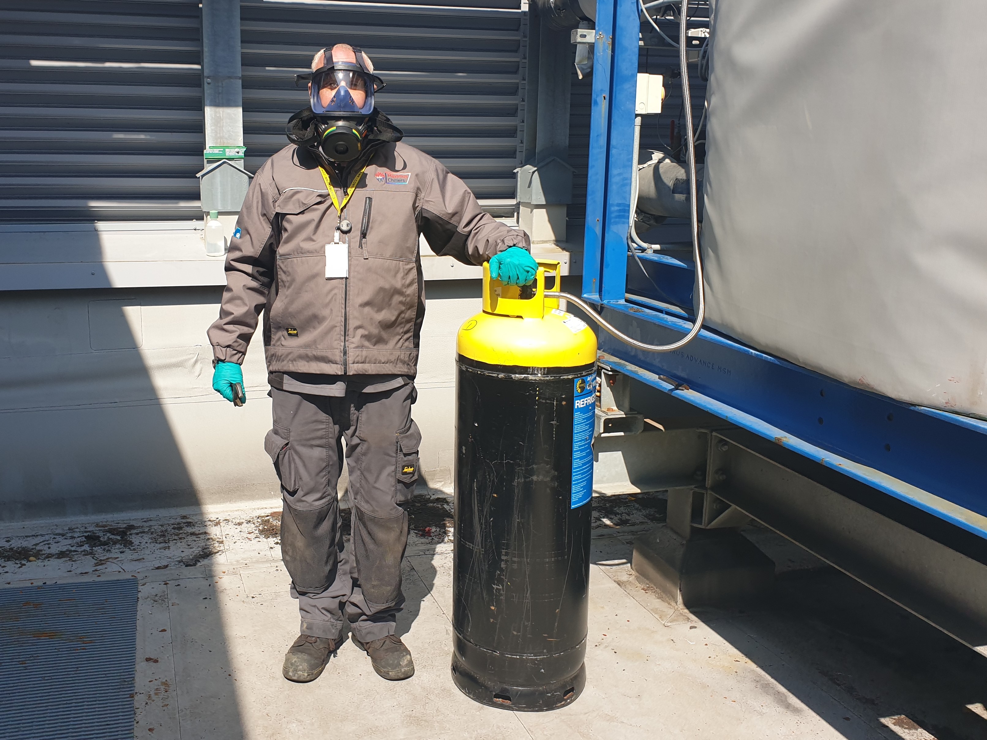 Industrial refrigeration ammonia being charged by an engineer wearing breathing apparatus and gloves