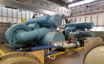 Two dark green centrifugal chillers undergoing maintenance in plant room