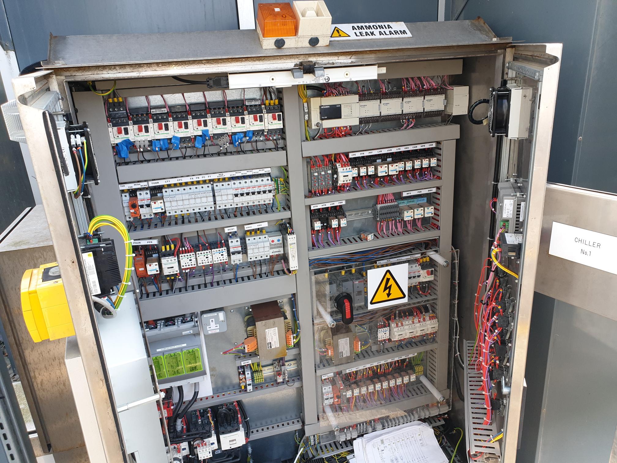 Open chiller controls panel showing PLC, relays, contactors and wiring