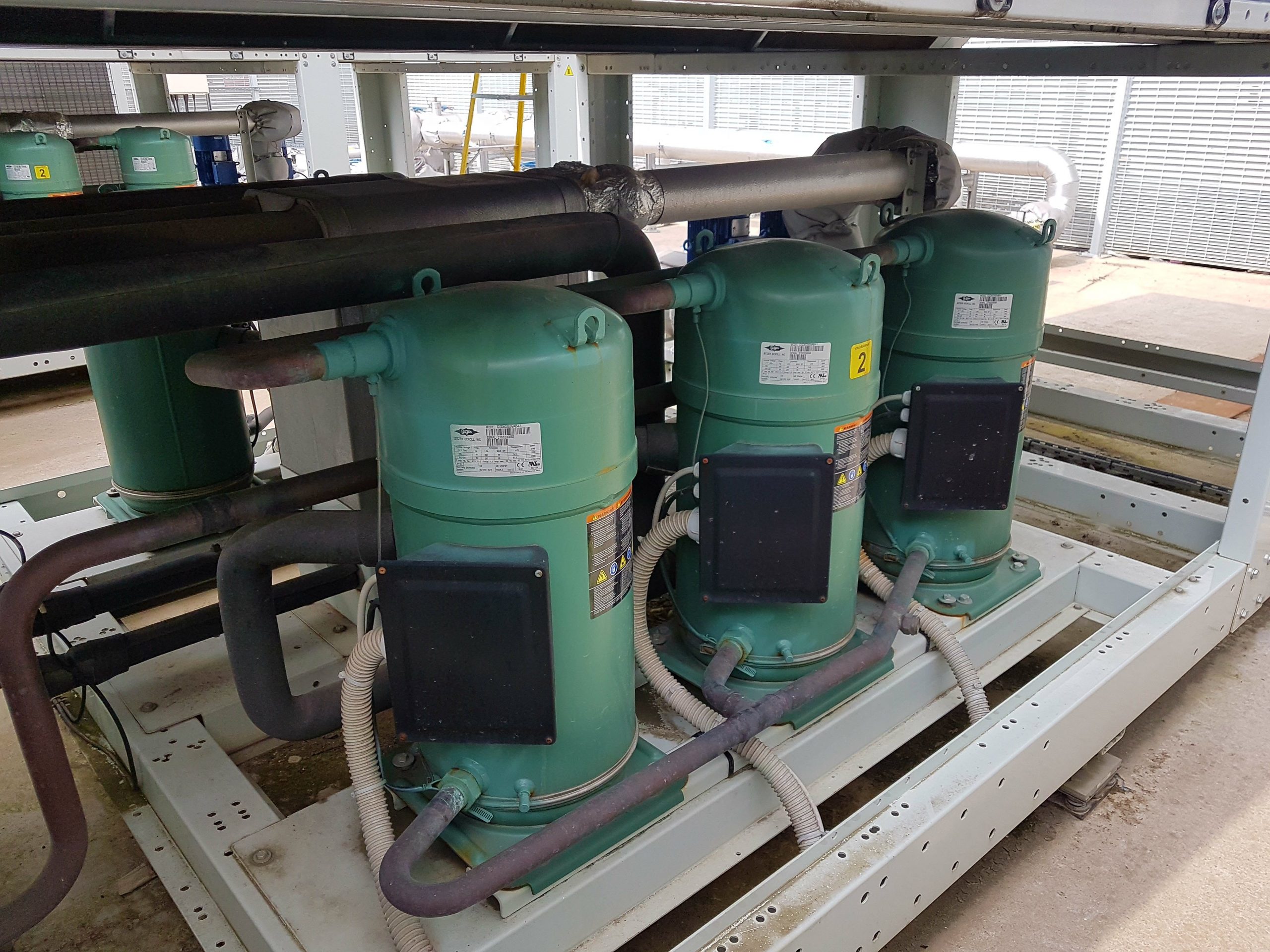 6 green Bitzer scroll compressors being maintained in a chiller