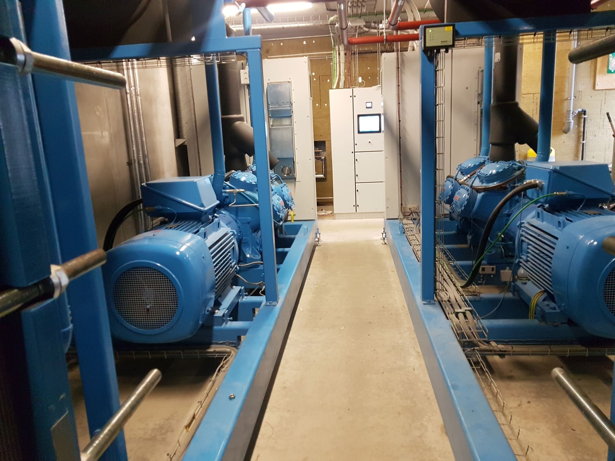 Two blue open drive Vilter reciprocating chiller compressors being maintained in a plant room