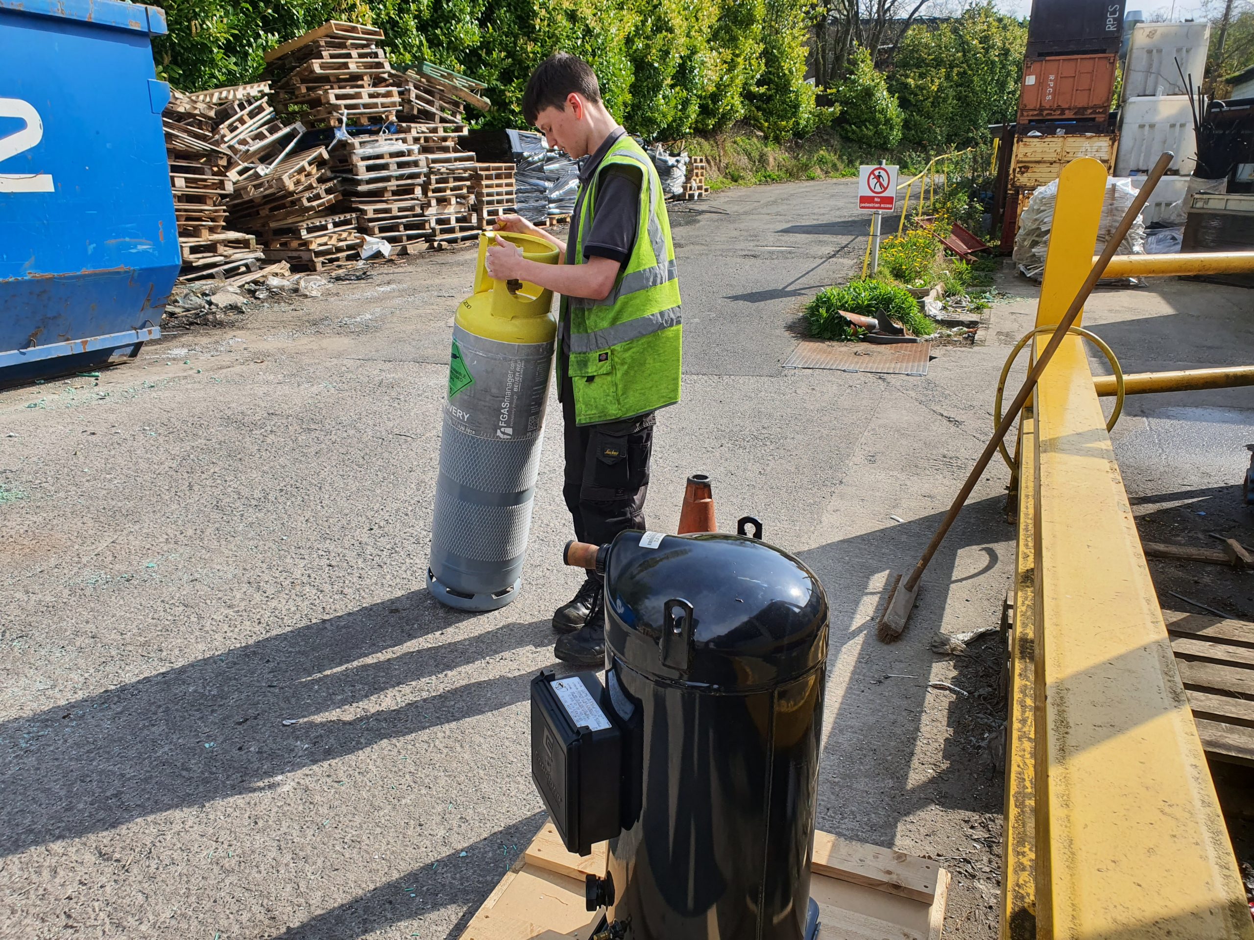A trainee moving a refrigerant cylinder during industrial chiller repair service