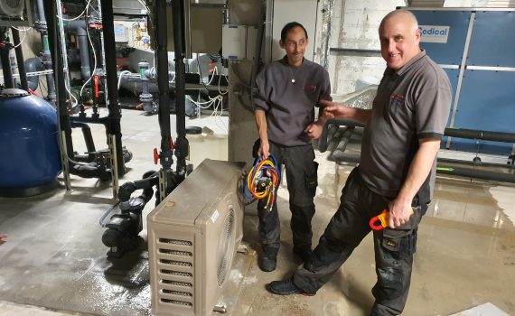 Two engineers in Marbella stood next to a chiller under repair in a plant room