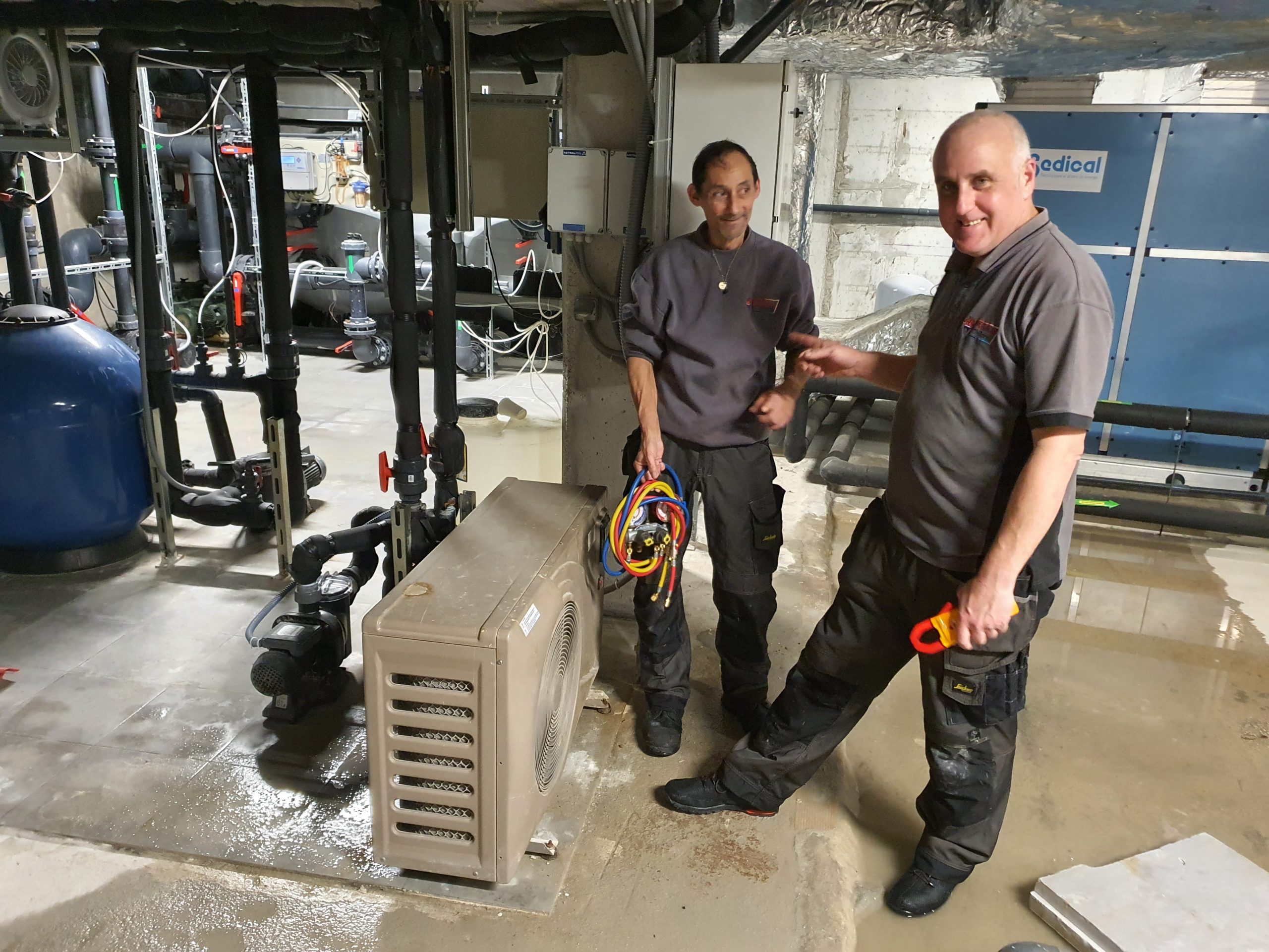 Two engineers in Marbella stood next to a chiller under repair in a plant room